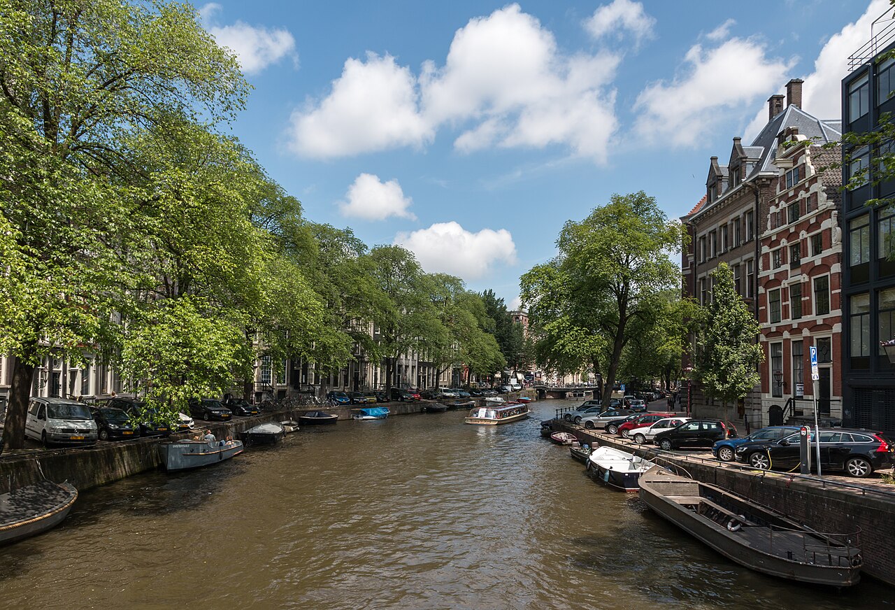 A leafy canal lined with houseboats and canal houses in central Amsterdam